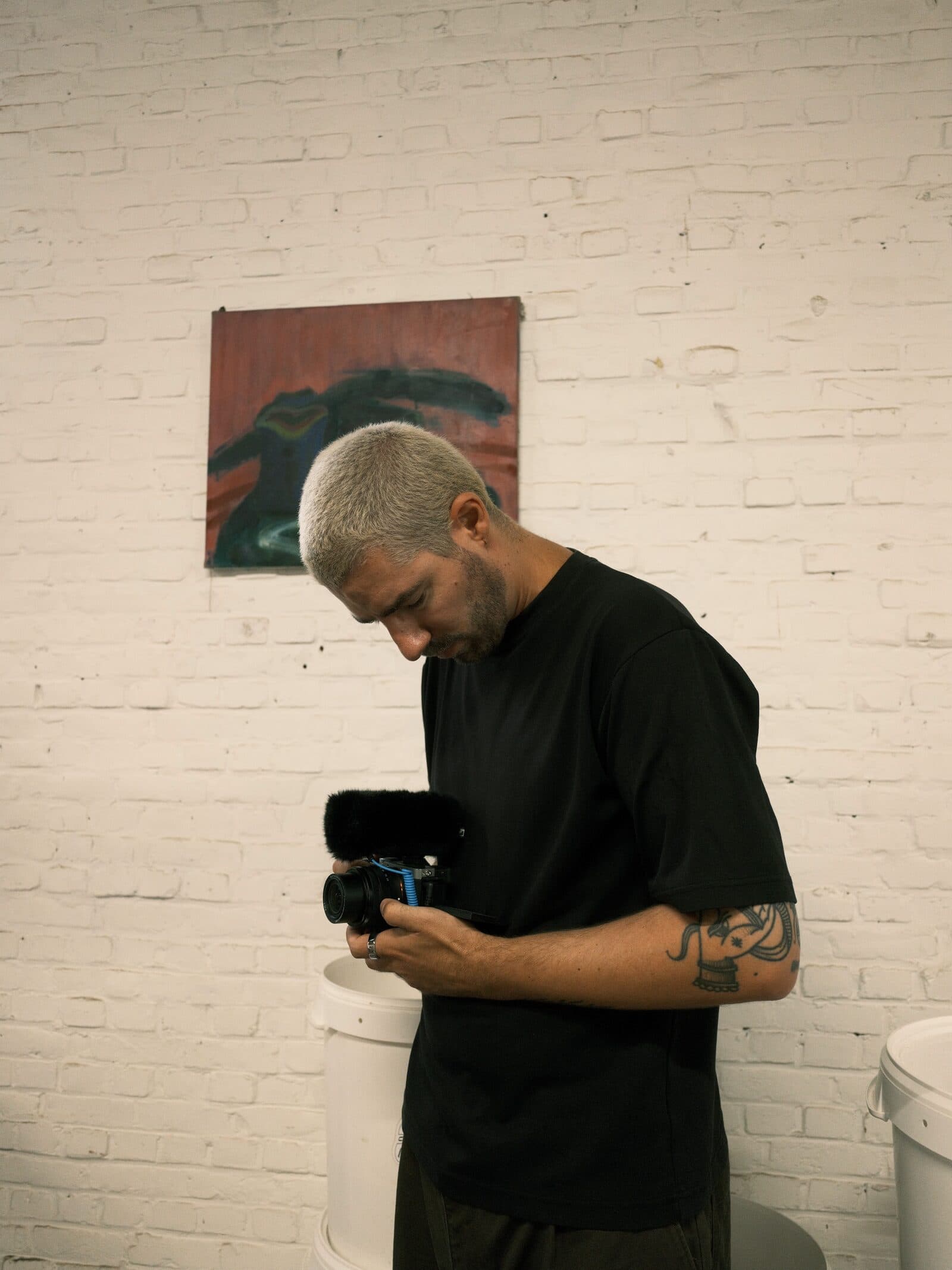 Jonas holding a camera in front of a white brick wall